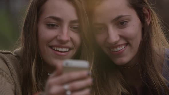 Up close view of teenage girls faces while they look at smartphone