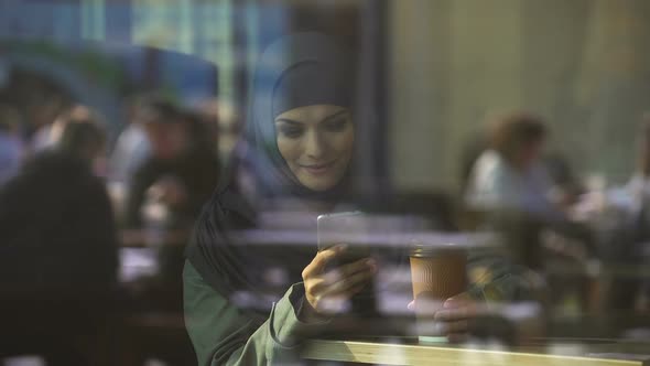 Beautiful Muslim Woman Using Mobile App for Online Shopping, Booking Hotel