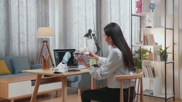 Asian Female Footwear Designer Looking At The Colorful Pattern Sneaker In Hands