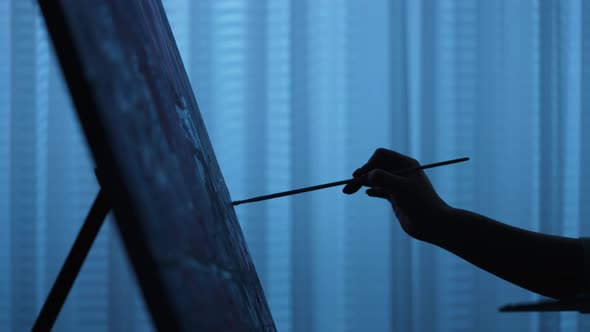 Silhouette of Woman's Hand Draws a Picture with Oil Paints on Canvas with a Brush