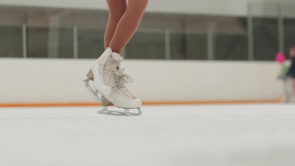 Close Up on the Ice Skates While Performing Figure Spinning on the Ice Rink