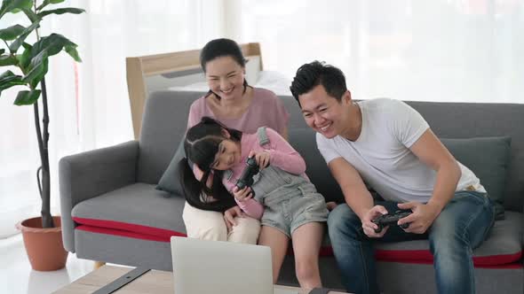 The daughter, father and mother were playing video games and having fun at home