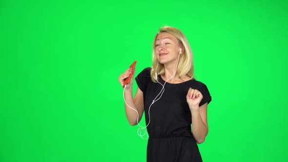 Cheerful Girl Walks in Headphones and with a Smartphone, Switches Music and Dancing. Chroma Key