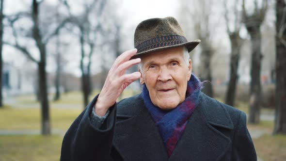 Old gentleman takes off his hat and looks in camera. Retired person 90 years old	