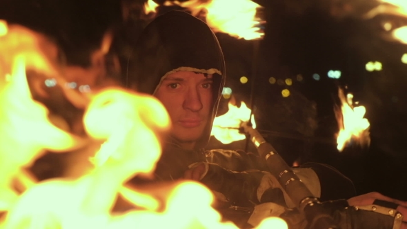 Fire Show Performance. Handsome Male Fire Juggler Performing Contact Manipulation with Fire Baton