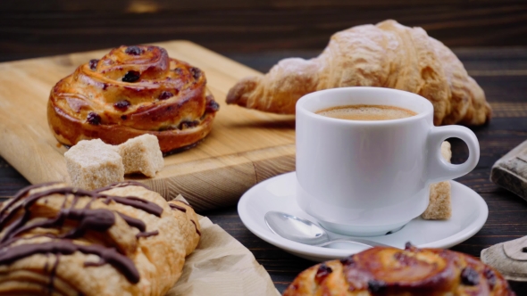 Cup of Coffee and Croissants on Wooden Background