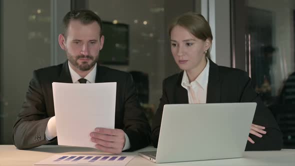 Executive Business People Reading Documents in Office at Night