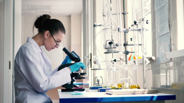 Young Woman Looking Through a Microscope. alt
