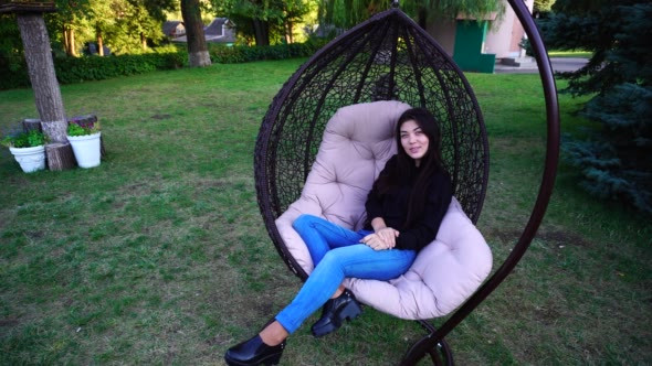 Attractive Lady Relaxes in Armchair, Looks Around