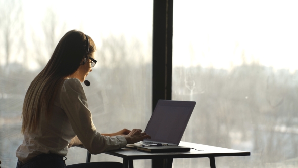 Smiling Businesswoman Using Headset Against Modern Room Overlooking City