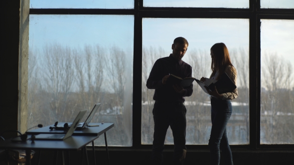 Businesspeople Silhouettes Standing Against Panoramic Office Window