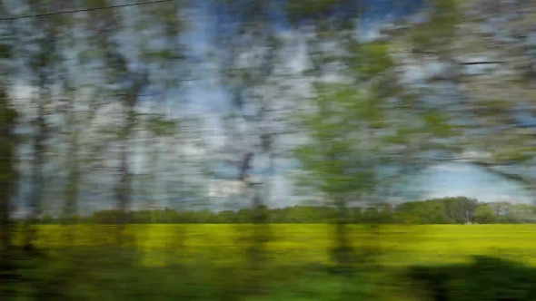 View From Riding Train Window of Coutryside Landscape Against Cloudy Sky