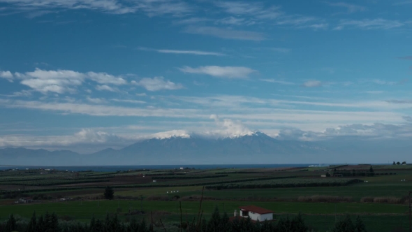 View of Picturesque Landscape with Mount Olympus and Countryside Against Flying Clouds in the Blue