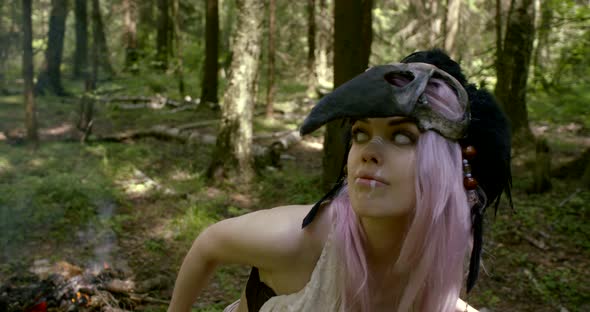 Lady with Pink Hair Wearing Mask on Head Stands in Forest