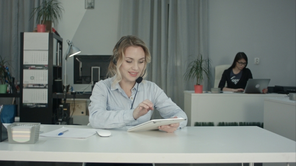 Focused Call Center Agent Using Digital Tablet at Her Workplace