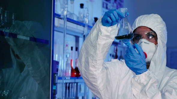 A Woman Looks at a Flask with Green Liquid