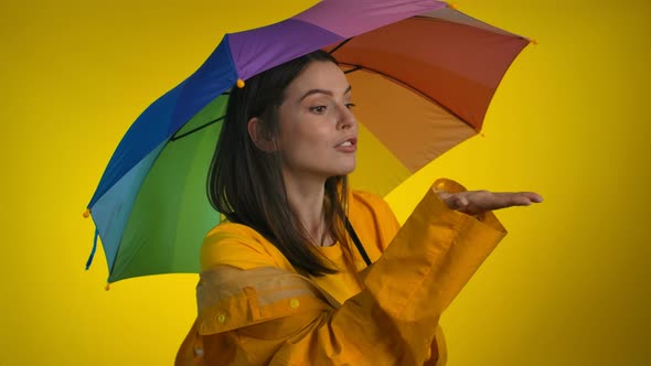 A Playful Woman in a Bright Yellow Raincoat with a Rainbow Umbrella