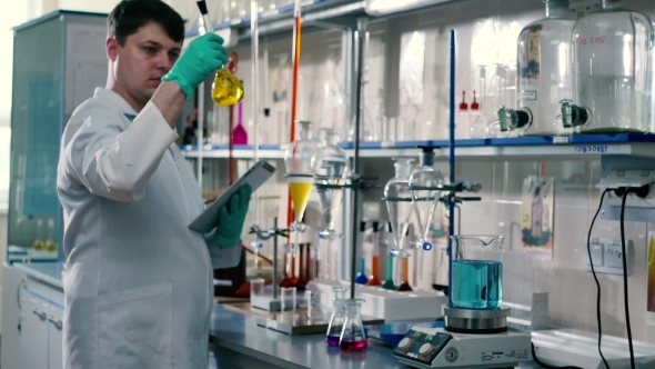 Man Scans the Liquid Standing in the Laboratory. alt