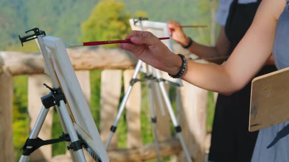 Hands of Painters Drawing Pictures on Easels Outdoors