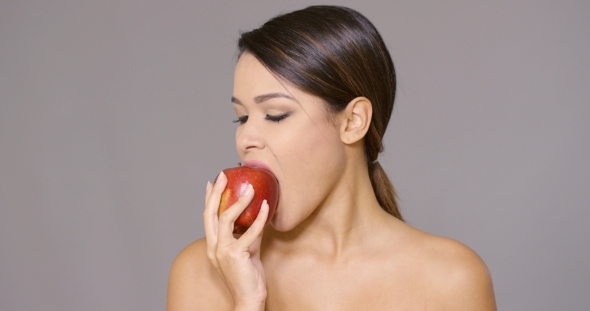 Young Woman Biting Into a Fresh Red Apple