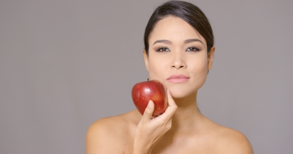 Calm Woman Holding an Apple Near Her Cheek
