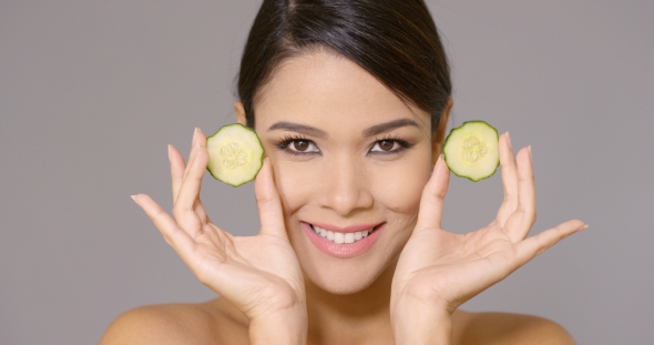 Grinning Woman Holding Cucumber Slices