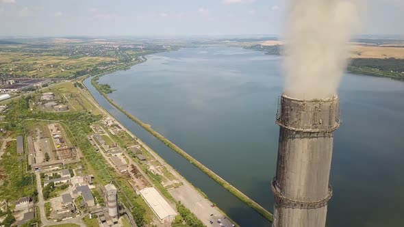 Aerial view of high chimney pipes with grey smoke from coal power plant