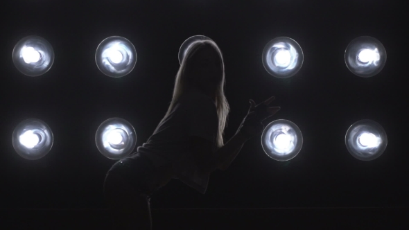 Silhouette of a Girl Dancing on the Background Lights.