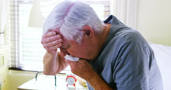 Sick senior man coughing in bedroom