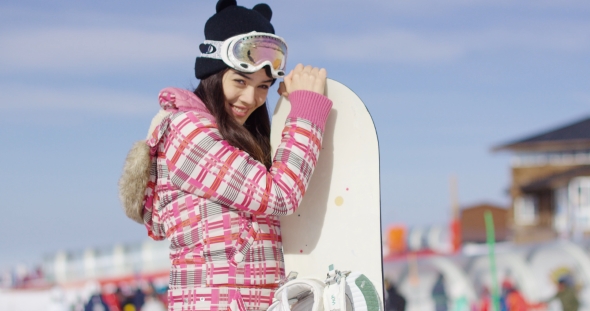 Cute Asian Female Snowboarder Relaxing on Slope