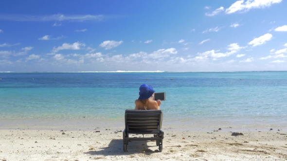 Woman with Pad Sun Bathing on the Coast of Blue Lagoon