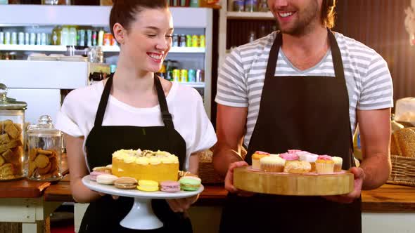 Portrait of waiter and waitress holding a tray of cupcakes