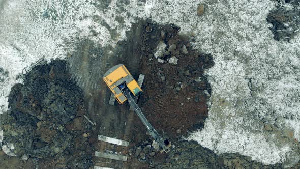 Excavator Digging Soil at a Construction Site. Top View of an Excavating Machine Digging Ground