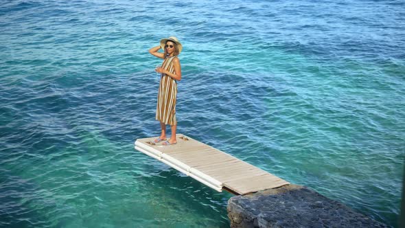 A woman with a glass of white wine on a dock over the Mediterranean Sea in Italy, Europe