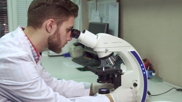 Man Looking Through the Microscope at the Laboratory