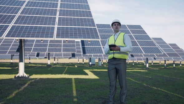 Solar Panel Technician Using Tablet Near Array