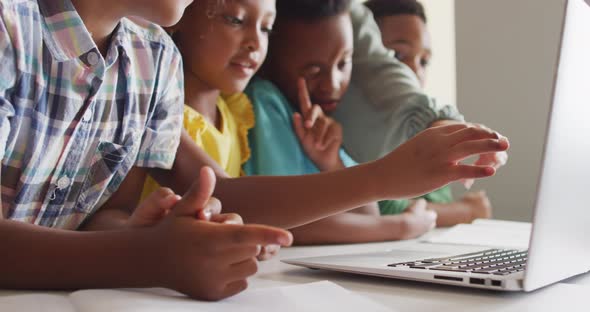 Video of hands of caucasian female teacher explaining lesson on laptop to diverse pupils