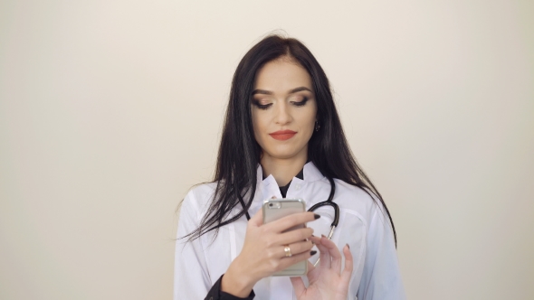 Pretty Female Doctor Using Mobile Phone on Background