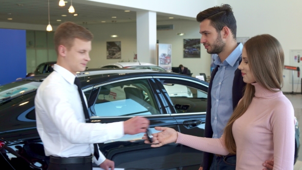 Salesman Gives the Car Key To the Couple at the Dealership