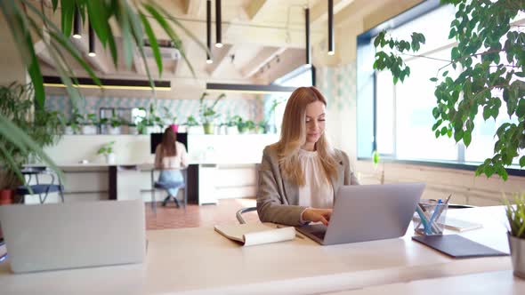 Young Businesswoman in Formal Suit Working at the Table in Modern Open Space Office