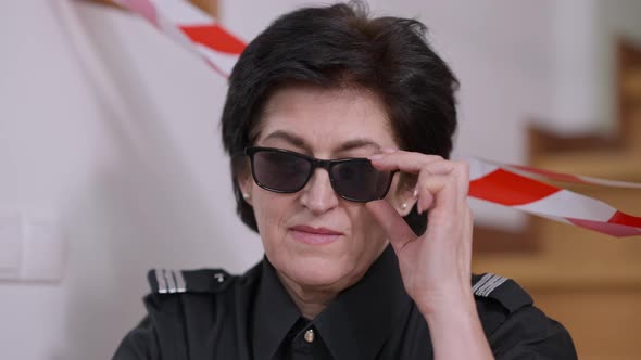 Headshot of Confident Senior Policewoman Putting Down Sunglasses and Looking at Camera