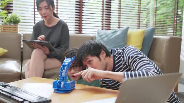 asian boy child with father mom control robot arm on Digital tablet and computer keyboard