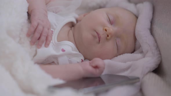 Closeup Portrait Sleeping Calm Infant Lying in Bed with Smartphone