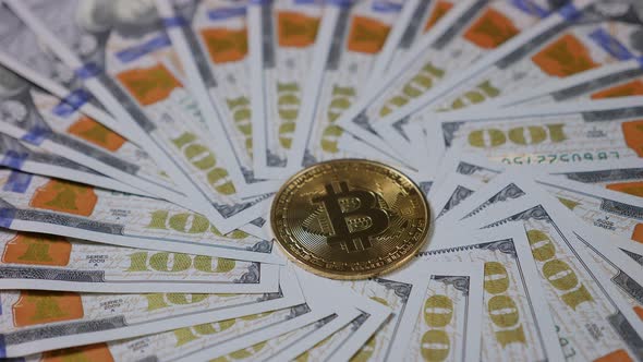 Closeup of a Hundred Dollar Bills and Gold Bitcoin Coins Spinning in a Circle