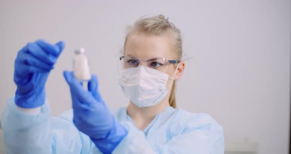 Female Scientist Holding Tubes and Flask with Liquid in Hands