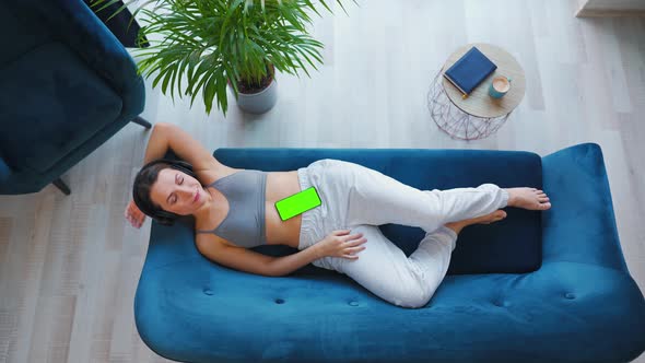 Overhead Shot of Relaxed Woman Listening to Lecture or Music in Headphones on Smartphone with Green