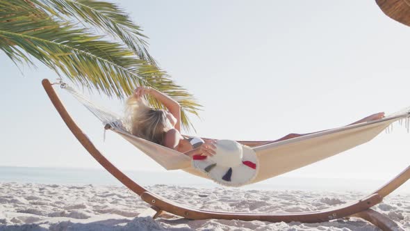 Caucasian woman lying on a hammock on the beach