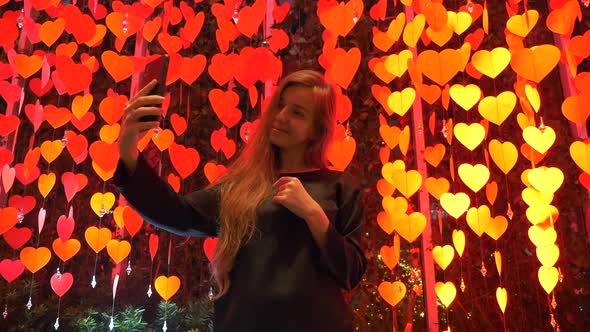 Girl Blogger with Mobile Phone Among Decoration with Red Hanging Paper Hearts