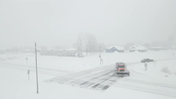 Drone view of sand filled snow plow trying to clear the highway in a blinding snowstorm.