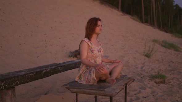 Orbit Young Woman Meditating Sitting on Wooden Bench at River During Sunset